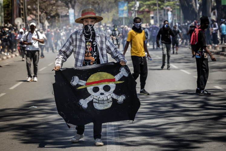 A student holds a flag bearing the logo of the Straw Hat Pirates from the popular Japanese manga &lsquo;One Piece&rsquo; on Oct. 9, 2025, during clashes with Malagasy security forces in Antananarivo amid a strike calling for constitutional reforms and the resignation of Madagascan President Andry Rajoelina.