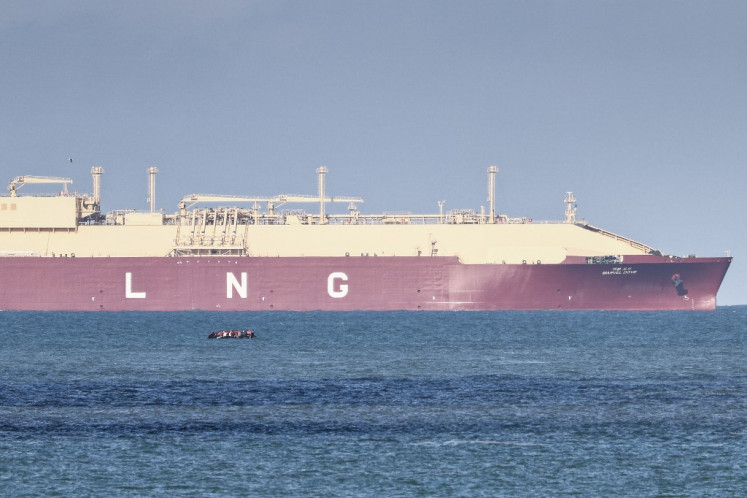 A LNG tanker ship makes its way past migrants attemping to cross the English channel on a smuggler's boat off the coast of Calais, north-western France, on Oct. 23, 2024.