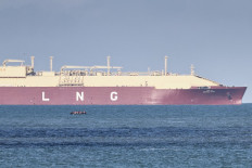 A LNG tanker ship makes its way past migrants attemping to cross the English channel on a smuggler's boat off the coast of Calais, north-western France, on Oct. 23, 2024.