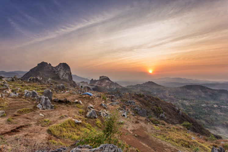 The sunset over the Stone Garden in Padalarang, West Java, casts golden light on ancient limestone formations.