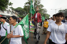 A man holds a flag showing the logo of Nahdlatul Ulama (NU), Indonesia's largest Islamic organization, during a parade for 'santri' (students of Islamic boarding schools) in Kediri, East Java, on Nov. 2, 2025.