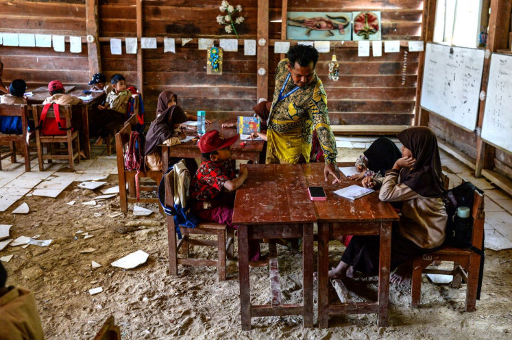 Class struggle: Teacher Armani checks his students’ work on Nov. 20, 2025 in their damaged classroom at SDN 2 state elementary school in Cibaliung village, Pandeglang regency, Banten. 