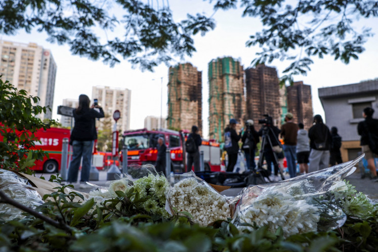 Flower tributes are pictured at a makeshift memorial on Friday with the Wang Fuk Court housing complex, site of a deadly fire, in the background in Tai Po district, Hong Kong, China.