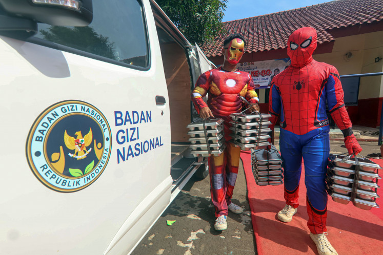 Heroic effort: Workers dressed as superheroes deliver free nutritious meals at SD Depok Baru 08 state elementary school in Depok, West Java, on Wednesday, Nov. 26. The National Nutrition Agency has recommended the use of potatoes and fish in school meals to avoid inflation.