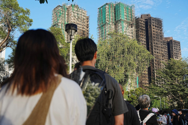 People queue to place flowers at a makeshift memorial near Wang Fuk Court housing estate to pay tribute to victims of the deadly fire at the Wang Fuk Court housing complex in Tai Po, Hong Kong on Nov. 29, 2025.