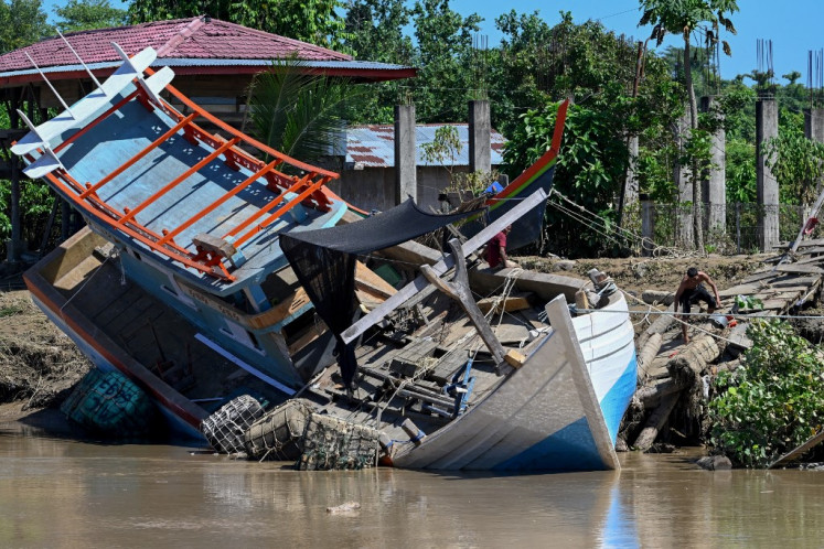 A fishermen boat is seen washed up ashore in the aftermath of flash floods in Meureudu, Pidie Jaya district in Aceh province on November 30, 2025. 