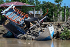 A fishermen boat is seen washed up ashore in the aftermath of flash floods in Meureudu, Pidie Jaya district in Aceh on November 30, 2025. 