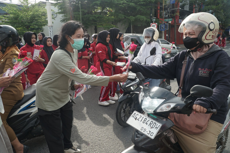 HIV/AIDS activists hand out roses and leaflets to passing motorists on Dec. 01, 2025, in Tulungagung, East Java. The sympathy campaign, held to mark World AIDS Day, aimed to raise public awareness of the dangers of HIV/AIDS and encourage high-risk groups to get early testing.