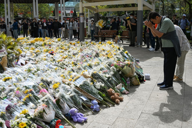 People lay flowers outside the Wang Fuk Court apartment blocks in the aftermath of the deadly November 26 fire in Hong Kong's Tai Po district on December 1, 2025. Police as well as Hong Kong's anti-corruption watchdog have launched investigations into the blaze that have killed at least 146 people, but a petition calling for greater accountability and demanding an independent probe was swiftly shut down as an organizer was reportedly arrested for sedition. 