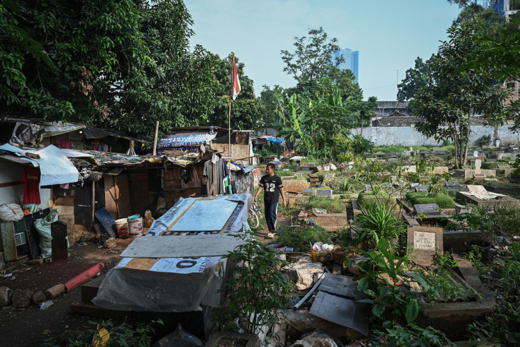 A man walks in front of his home on Tuesday inside the Menteng Pulo II public cemetery (TPU) in East Jakarta. The Jakarta administration is relocating 105 families residing inside the cemetery to Jagakarsa Rusunawa (low-cost rental apartment) in a bid to resolve the shortage of burial plots for the dead in the city.