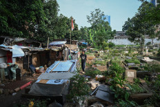 A man walks in front of his home on Tuesday inside the Menteng Pulo II public cemetery (TPU) in East Jakarta. The Jakarta administration is relocating 105 families residing inside the cemetery to Jagakarsa Rusunawa (low-cost rental apartment) in a bid to resolve the shortage of burial plots for the dead in the city.