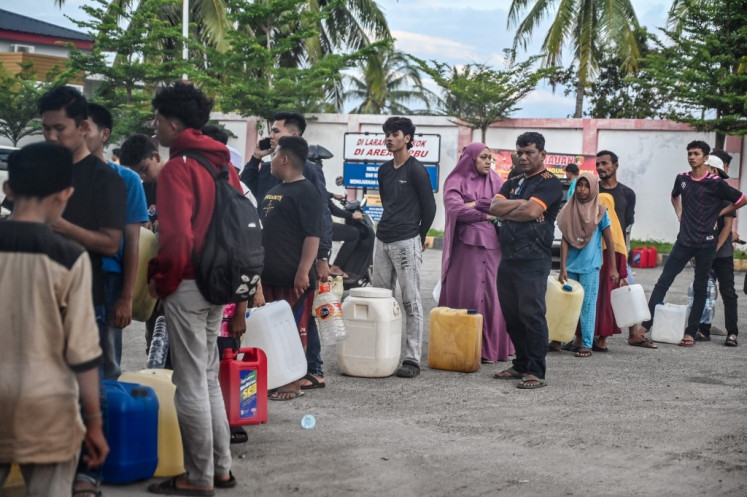 Flood-affected residents wait in line to receive fuel at a gas station in Samahani, Aceh province on December 2, 2025. 