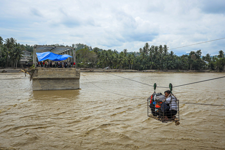 Villagers use a makeshift cable car to cross the river on Dec. 2, 2025, after the bridge was destroyed by a flash flood in Bireuen, Aceh. 