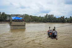 Villagers use a makeshift cable car to cross the river on Dec. 2, 2025, after the bridge was destroyed by a flash flood in Bireuen, Aceh. 