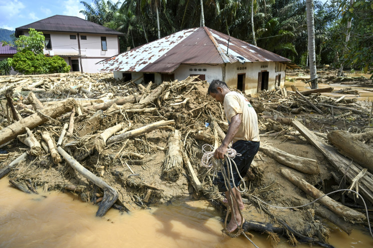 A villager affected by flash floods walks amongst a pile of log debris on Dec. 2, 2025, in Tukka village, Central Tapanuli regency, North Sumatra. The death toll from floods and landslides that have struck Indonesia's Sumatra island since late November has risen to 712, the National Disaster Management Agency said on Dec. 2. 