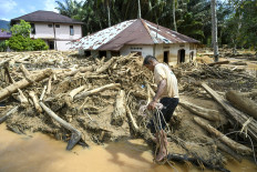 A villager affected by flash floods walks amongst a pile of log debris on Dec. 2, 2025, in Tukka village, Central Tapanuli regency, North Sumatra. The death toll from floods and landslides that have struck Indonesia's Sumatra island since late November has risen to 712, the National Disaster Management Agency said on Dec. 2. 