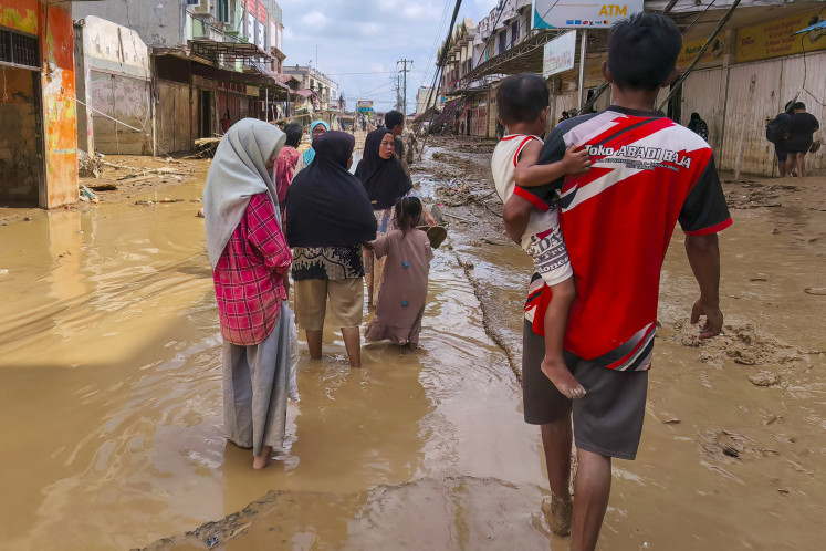 Flood-affected residents walk along a muddy road in Kuala Simpang village in Aceh Tamiang, North Sumatra on Dec. 2, 2025. 