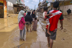 Flood-affected residents walk along a muddy road in Kuala Simpang village in Aceh Tamiang, North Sumatra on Dec. 2, 2025. 