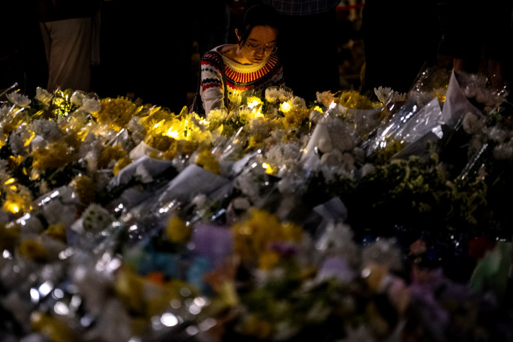 A woman lays flowers during a vigil held outside the Wang Fuk Court apartment blocks in the aftermath of the deadly Nov. 26 fire in Hong Kong's Tai Po district on Dec. 2, 2025. The fire engulfed seven residential towers under renovation in the north of the city, killing at least 156 people, displacing thousands more and fueling public demands for accountability. 