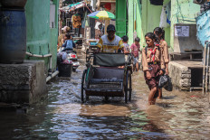 Road users pass through tidal flooding in Muara Angke, Jakarta, on Dec. 3, 2025. The Meteorology, Climatology and Geophysics Agency (BMKG) has forecast potential tidal flooding in several parts of Jakarta&rsquo;s northern coast until Dec. 10, 2025, caused by maximum sea tide conditions coinciding with the full moon phase, which could significantly increase sea levels. 