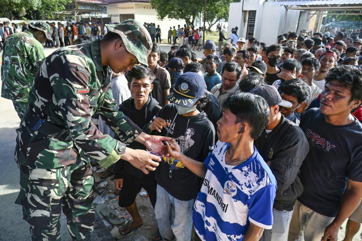 Villagers receive free sacks of rice from the Indonesian Military, distributed amid relief efforts from the government's rice warehouse at Sarudik, in Central Tapanuli, North Sumatra province, on December 3, 2025. 