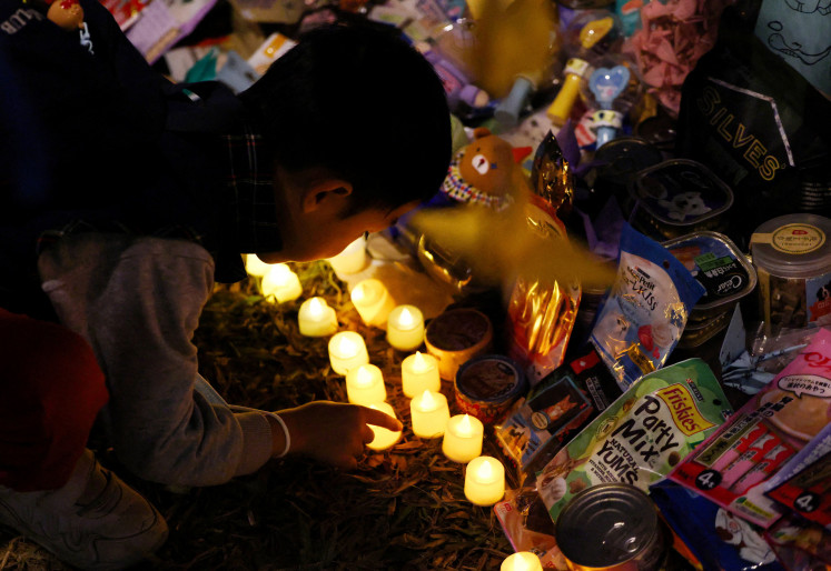 A boy places an electric candle at the section of the makeshift memorial devoted to animals that died in the Wang Fuk Court housing complex last week’s deadly fire, on Dec. 3 in Tai Po, Hong Kong, China.