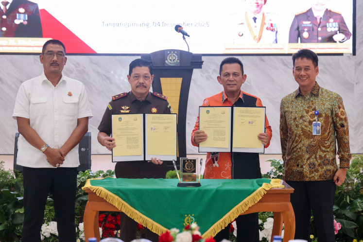 Riau Islands Governor Ansar Ahmad (center right) and J. Devy Sudarso (center left), head of the Riau Islands Prosecutor's Office, hold up copies of a memorandum of understanding on community sentences on Dec. 4, 2025, during a signing ceremony in provincial capital Tanjungpinang.