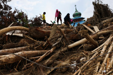 Residents walk on debris as they visit their homes following deadly flash flood in Batang Toru, South Tapanuli, North Sumatra, December 6, 2025. 