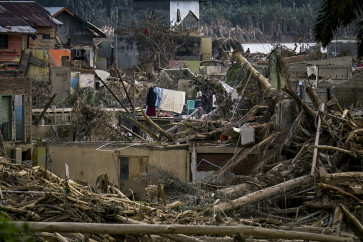 A woman hangs up clothes to dry on Dec. 6 amid devastation caused by a flash flood that struck  Aceh Tamiang, Aceh province. Ruinous floods and landslides have killed more than 900 people in Sumatra, officials said on Dec. 6, with fears that starvation could send the toll even higher. 