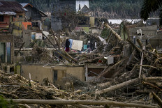 A woman hangs up clothes to dry on Dec. 6 amid devastation caused by a flash flood that struck  Aceh Tamiang, Aceh province. Ruinous floods and landslides have killed more than 900 people in Sumatra, officials said on Dec. 6, with fears that starvation could send the toll even higher. 