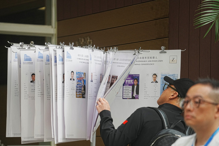 A voter checks on the candidates at a polling station in Tai Po during the Legislative Council general election in Hong Kong on December 7, 2025.