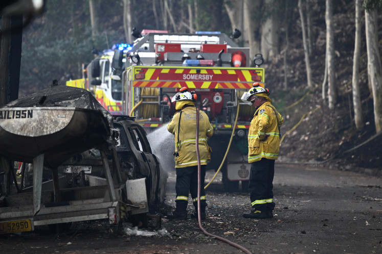 Firefighters work at the site where bushfire destroyed homes along Glenrock Parade, in Koolewong on the Central Coast of New South Wales, Australia on December 6, 2025.