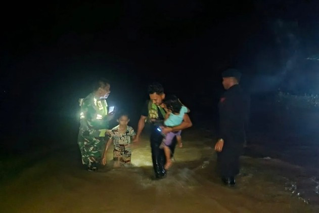An Indonesian Army soldier (left) and an Aceh Police Mobile Brigade personnel (right) help a man and two children evacuate through a flood on Nov. 29, in Central Trumon district, South Aceh regency, Aceh. The provinces of Aceh, North Sumatra and West Sumatra were badly hit by flooding and landslides caused by an extreme weather. 