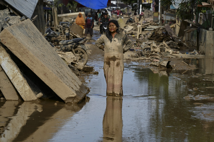 A woman covered in mud stands on a street filled with mud on Saturday after a flash flood hit the area in Aceh Tamiang, Aceh province. Ruinous floods and landslides have killed more than 900 people in Sumatra, the National Disaster Mitigation Agency (BNPB) said on Saturday, with fears that starvation could send the toll even higher. 