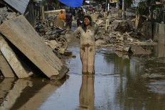 A woman covered in mud stands on a street filled with mud on Saturday after a flash flood hit the area in Aceh Tamiang, Aceh province. Ruinous floods and landslides have killed more than 900 people in Sumatra, the National Disaster Mitigation Agency (BNPB) said on Saturday, with fears that starvation could send the toll even higher. 