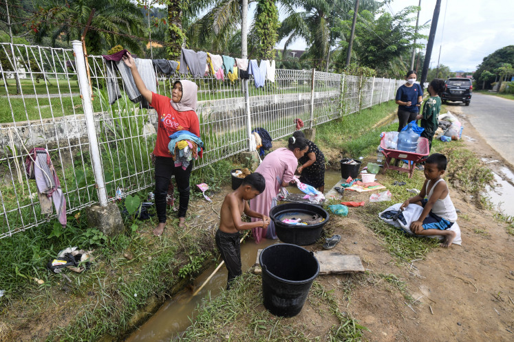 Water crisis: Residents wash clothes and bathe in a drainage ditch on Saturday, Dec. 6, 2025, in Central Tapanuli, North Sumatra. A week after landslides and floods hit the area, locals still have no access to clean water and are forced to use ditch water for their daily needs.