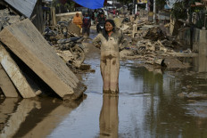 A woman covered in mud stands on a street filled with mud after a flash flood hit the area in Aceh Tamiang, Aceh, on Dec. 6, 2025. 