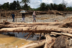 Local residents walk on logs used as a temporary bridge following a deadly flash flood on Dec. 7 in Batang Toru, South Tapanuli, North Sumatra. 