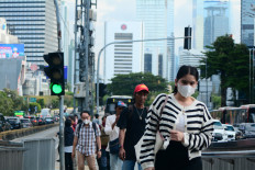A pedestrian wearing a mask is seen walking in front of the Tosari Transjakarta bus shelter in Central Jakarta on Dec. 8, 2025. 