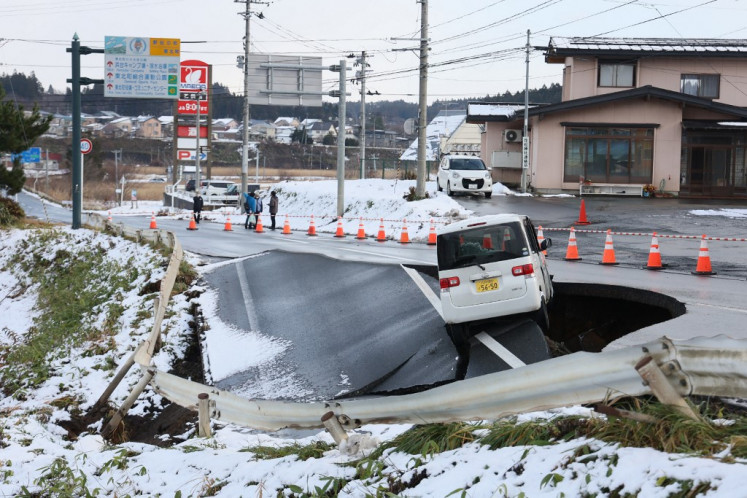 A vehicle rests on the edge of a collapsed road in Tohoku town in Aomori Prefecture on December 9, 2025, following a 7.5 magnitude earthquake off northern Japan. A big quake off northern Japan left at least 30 injured, authorities said on December 9, damaging roads and leaving thousands without power in freezing temperatures. 