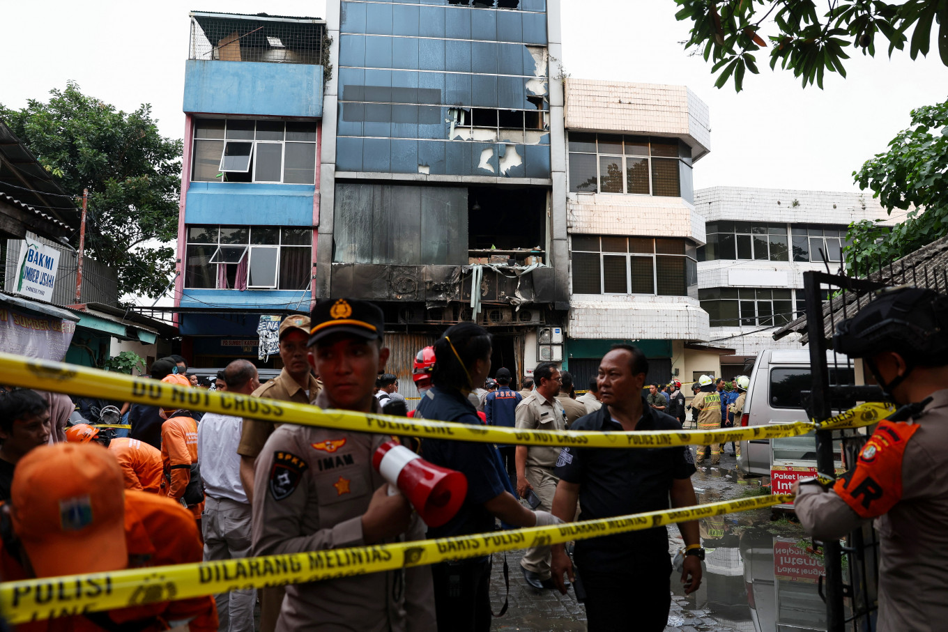 Police officers stand near a seven-story building damaged by fire, in Jakarta, December 9, 2025.