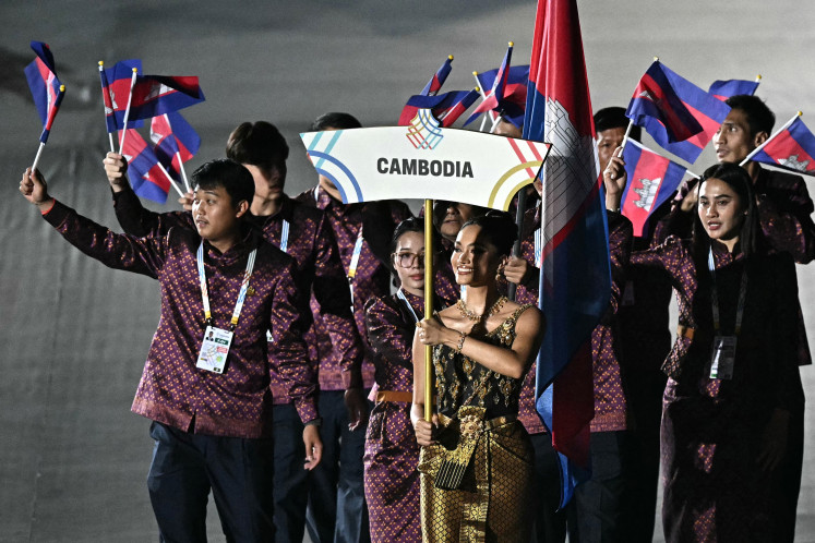 Members of Cambodia's delegation wave their country's national flag as they take part in the athletes' parade during the opening ceremony of the 33rd SEA Games at Rajamangala National Stadium in Bangkok on December 9, 2025. Cambodia withdrew on December 10, 2025 from the Southeast Asian Games, a Games official said, as a border conflict with hosts Thailand escalated and forced a mass exodus of civilians from both sides of the disputed frontier.