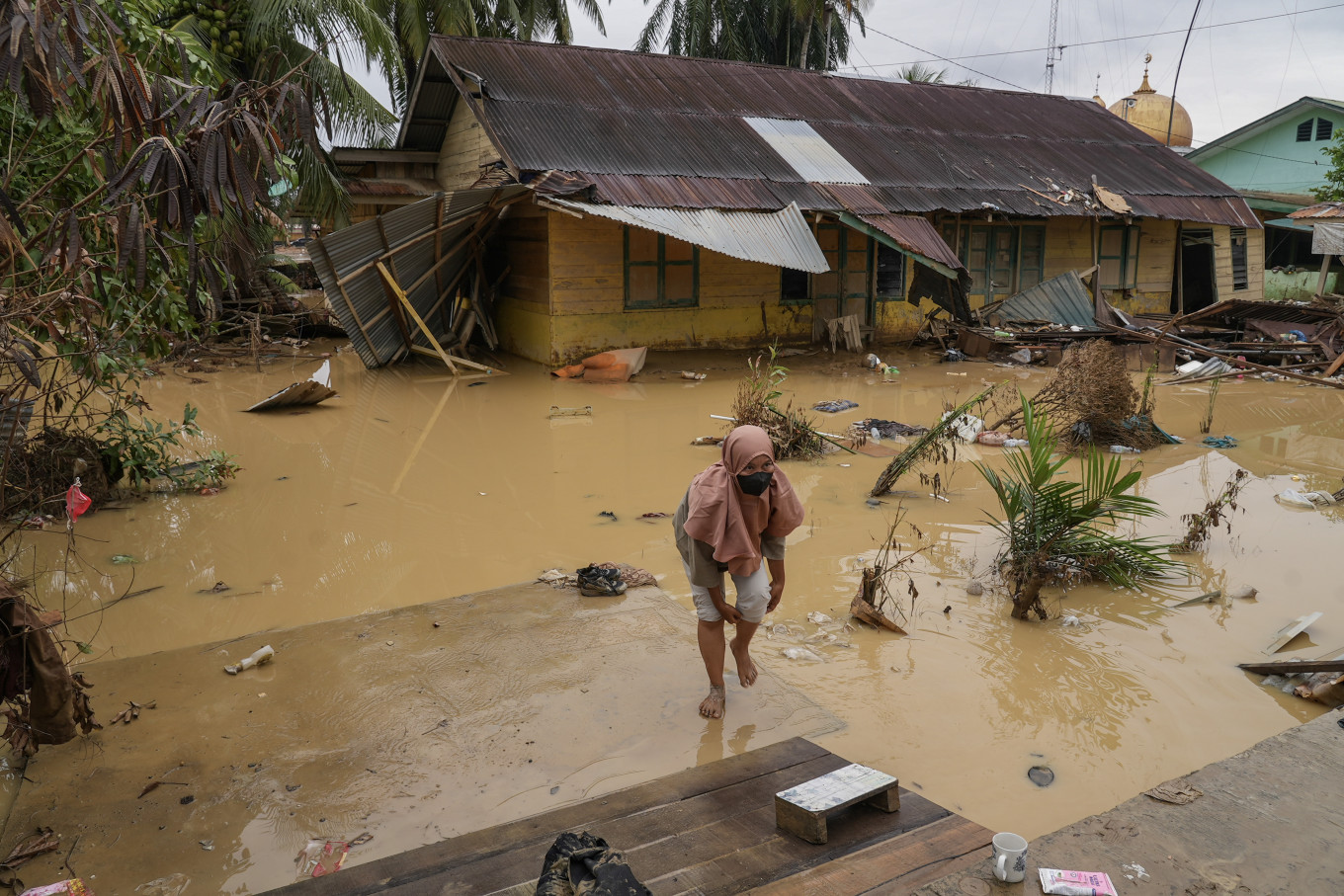 A resident walks past a house destroyed by flooding in Bundar Village, Karang Baru, Aceh Tamiang Regency, Aceh, on Tuesday, Dec. 9, 2025. 