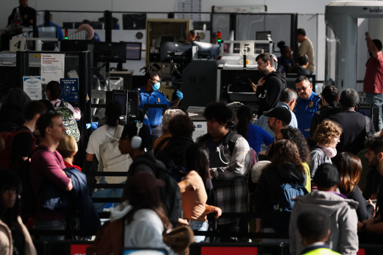 Passengers wait in line for a Transportation Security Administration (TSA) security checkpoint while traveling at Los Angeles International Airport (LAX) in Los Angeles, on November 26, 2025.