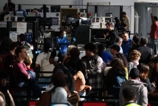 Passengers wait in line for a Transportation Security Administration (TSA) security checkpoint while traveling at Los Angeles International Airport (LAX) in Los Angeles, on November 26, 2025.