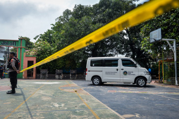 Police officers stand guard on Dec. 11, 2025, near the free-meals delivery vehicle that struck students and a teacher at SDN Kalibaru 01 Pagi state elementary school in Cilincing, North Jakarta. The incident left 20 students and one teacher injured and requiring treatment at nearby hospitals.