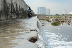 Seawater counterflow: A motorist passes on Dec. 6 along the side of a giant seawall that appears to have cracked in several sections, allowing seawater to overflow into residential areas in Muara Baru, North Jakarta.