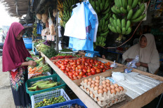 Disrupted market: A woman selects vegetables sold by vendors on Dec. 9, 2025, at the Pangwa traditional market in Pidie Jaya, Aceh. The government has reported rising prices of key staple foods across various regions as widespread flooding in northern Sumatra and torrential rains continue to disrupt harvests and supply chains.