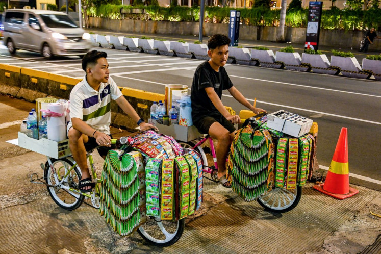 On the road: Mobile coffee vendors wait for customers in a shopping area near the Hotel Indonesia traffic circle in Central Jakarta on Oct. 27, 2024.