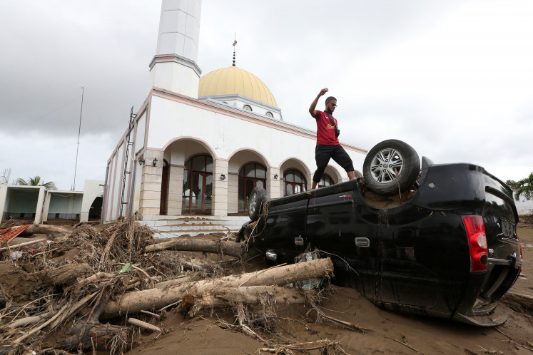 People stand atop vehicles damaged by flooding from the overflowing Meureudu River on Dec. 13 at the yard of Dayah Tgk Chik Pante Geulima Mosque in Pidie Jaya, Aceh, Indonesia. According to preliminary data from the emergency response services, flooding since the river overflowed on Nov. 26 damaged or inundated 122 places of worship and 10,530 homes, forcing 5,729 families, or 20,114 people, to evacuate. 